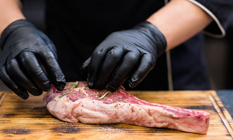 Behandschute Hände marienieren ein Stück Fleisch