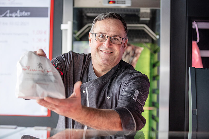 Metzger hält verpackte Wurstwaren in die Kamera